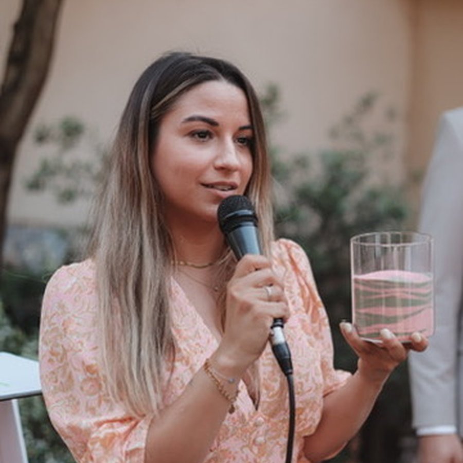 Jasmin mit Mikrofon und Sanduhr-Glas während der Zeremonie